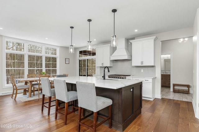kitchen featuring custom range hood, a sink, decorative backsplash, dark wood finished floors, and white cabinetry