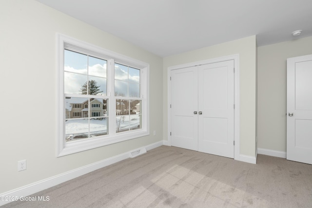unfurnished bedroom with carpet, baseboards, and a closet