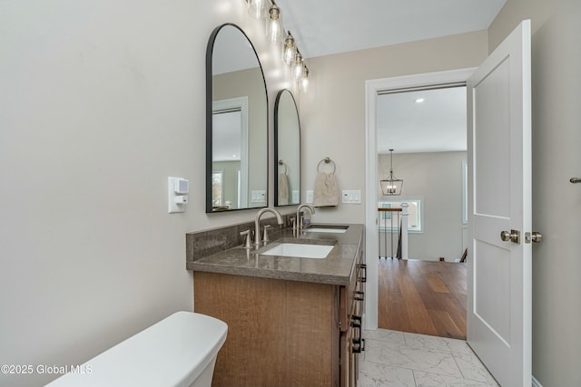 bathroom featuring marble look tiles, double vanity, and toilet