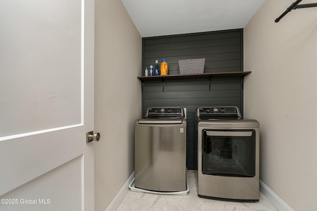 clothes washing area with separate washer and dryer and baseboards
