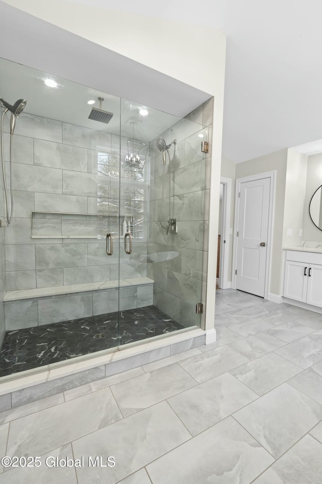bathroom with marble finish flooring, a shower stall, baseboards, and vanity