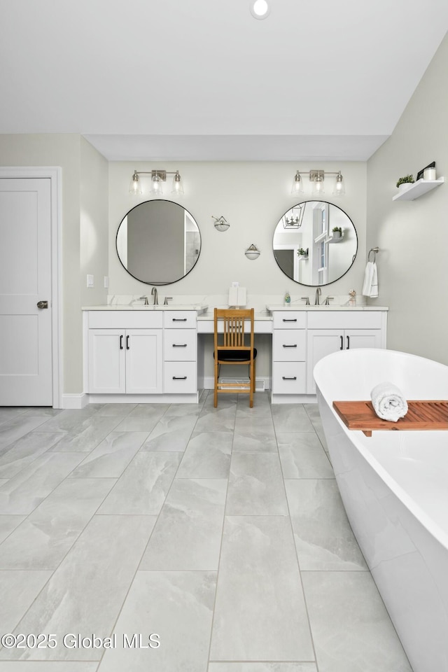 bathroom featuring a freestanding tub, two vanities, baseboards, marble look tile flooring, and recessed lighting
