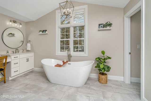 full bathroom featuring baseboards, a chandelier, vanity, lofted ceiling, and marble look tile flooring