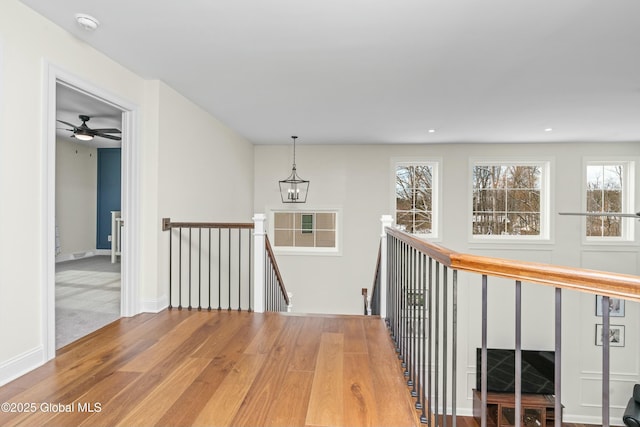 hallway with an upstairs landing, wood finished floors, recessed lighting, and baseboards