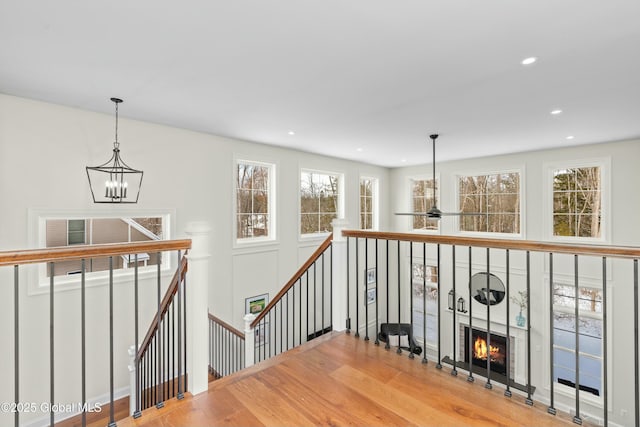 corridor featuring an upstairs landing, a chandelier, healthy amount of natural light, wood finished floors, and recessed lighting