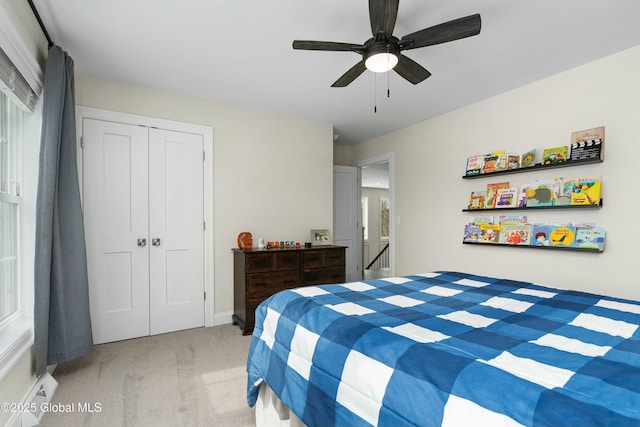 bedroom with light colored carpet, a closet, a ceiling fan, and baseboards