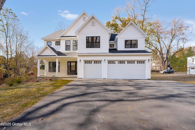 view of front of home featuring asphalt driveway, board and batten siding, an attached garage, covered porch, and a shingled roof