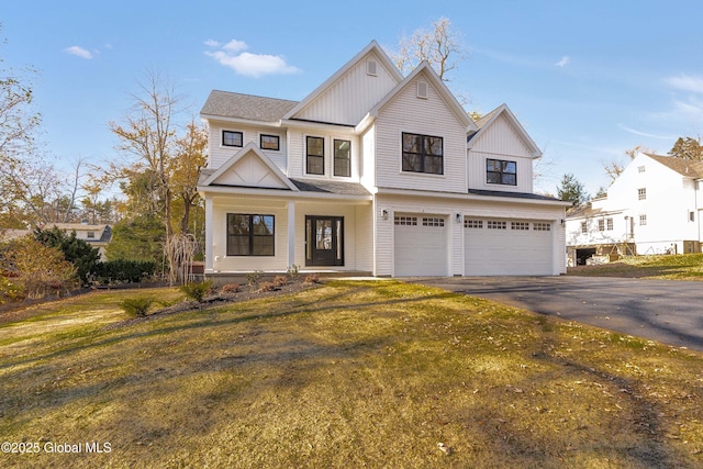 view of front of house featuring an attached garage, driveway, board and batten siding, covered porch, and a front yard