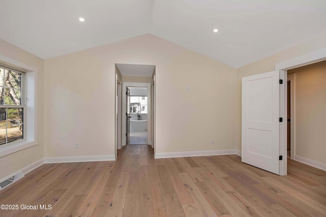 empty room with healthy amount of natural light, lofted ceiling, light wood-style flooring, baseboards, and recessed lighting