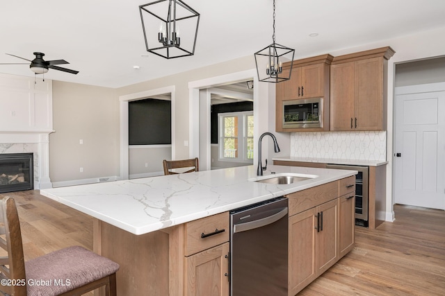 kitchen with stainless steel appliances, a sink, wine cooler, an island with sink, and a chandelier