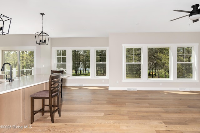 dining area with light wood-type flooring, a ceiling fan, and baseboards