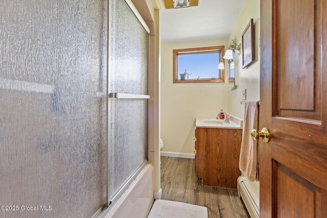 18 Main St, Berne, NY 12059 - full bath with a baseboard radiator, wood finished floors, vanity, toilet, and shower / bath combination with glass door