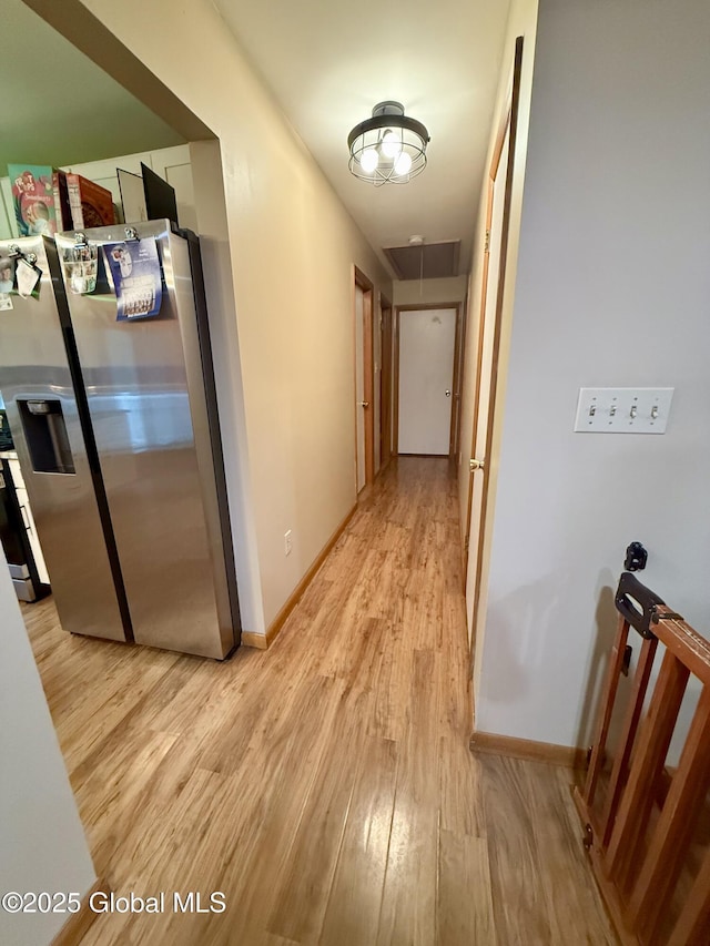 hall with light wood-style flooring, attic access, and baseboards