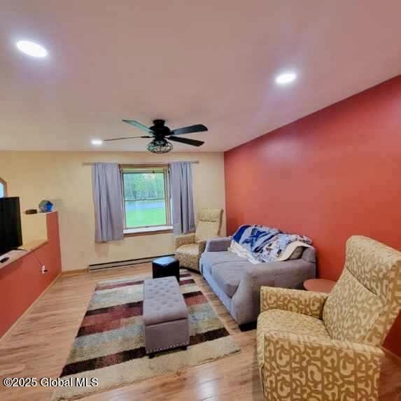 living room featuring wood finished floors, a ceiling fan, recessed lighting, and a baseboard radiator