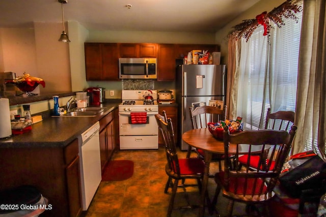 kitchen featuring appliances with stainless steel finishes, a sink, plenty of natural light, and dark countertops