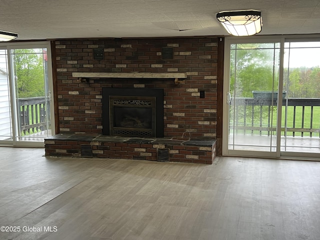 2299 Coach Rd, Argyle, NY 12809 - unfurnished living room featuring wood finished floors, plenty of natural light, a brick fireplace, and a wall of windows