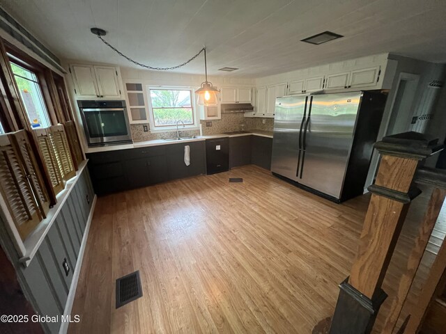 2299 Coach Rd, Argyle, NY 12809 - kitchen featuring stainless steel appliances, a sink, under cabinet range hood, light wood finished floors, and backsplash
