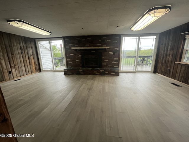 2299 Coach Rd, Argyle, NY 12809 - unfurnished living room featuring wood walls, wood finished floors, healthy amount of natural light, and a brick fireplace
