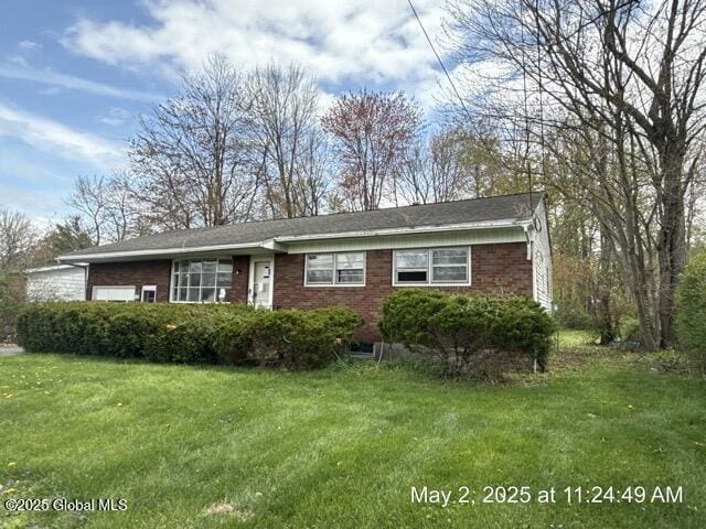 view of front of house featuring a garage, brick siding, and a front lawn