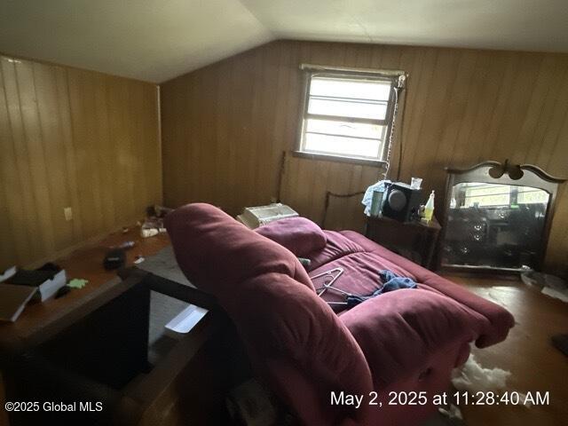 bedroom with wooden walls, lofted ceiling, and carpet flooring