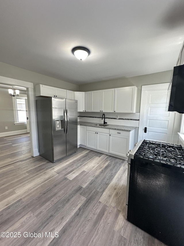 kitchen featuring appliances with stainless steel finishes, white cabinetry, light wood finished floors, and a sink