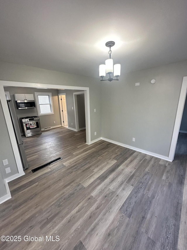 unfurnished dining area featuring dark wood finished floors, a chandelier, and baseboards