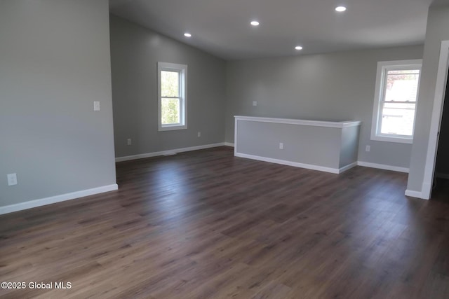 empty room with dark wood-style flooring, lofted ceiling, baseboards, and recessed lighting