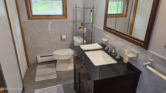 505 Elm Ave, Bethlehem, NY 12158 - bathroom featuring a baseboard heating unit, tile walls, toilet, vanity, and tile patterned floors