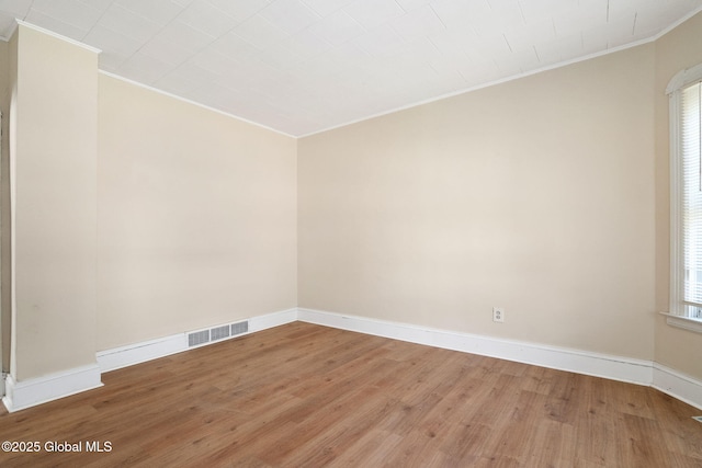 unfurnished room featuring ornamental molding, wood finished floors, and baseboards