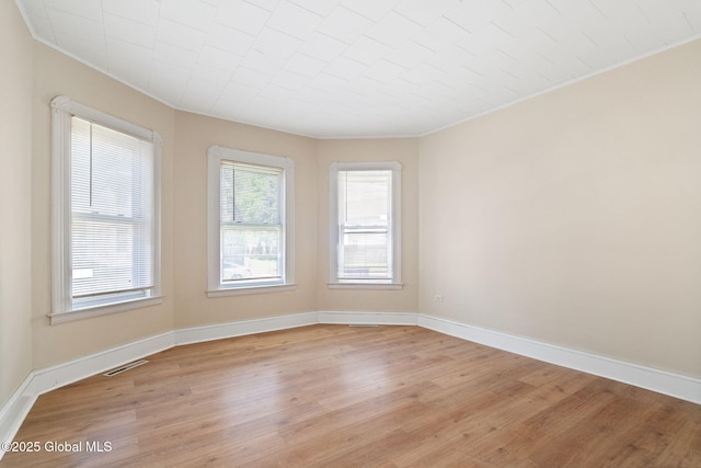 unfurnished room featuring light wood-style flooring, crown molding, and baseboards