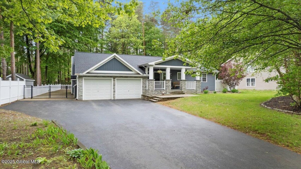 7 Wineberry Ln, Malta, NY 12020 - view of front facade with asphalt driveway, a garage, covered porch, and stone siding