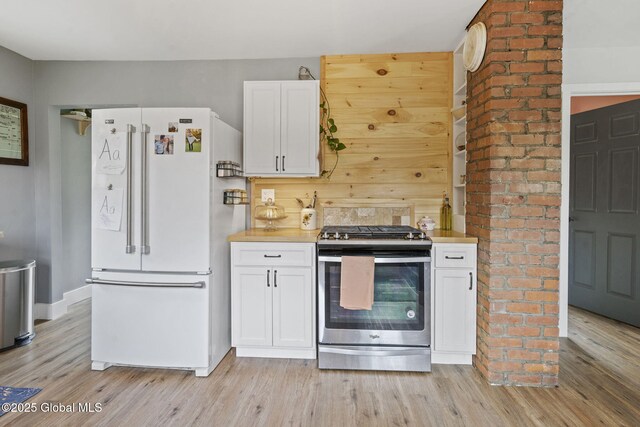 109 Wood Rd, Ballston Spa, NY 12020 - kitchen featuring freestanding refrigerator, stainless steel range with gas stovetop, light wood finished floors, and white cabinets