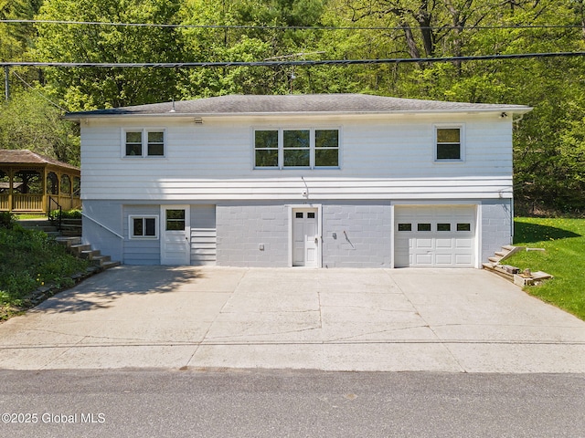 view of front of home with driveway, a garage, and stairs