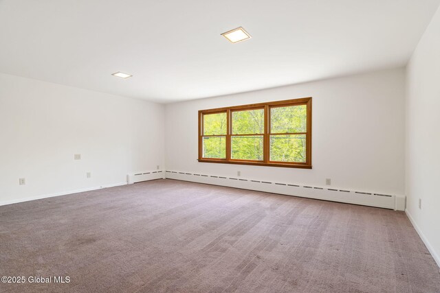 carpeted empty room featuring a baseboard heating unit and baseboards