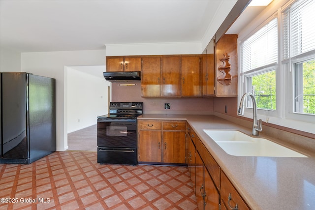 kitchen featuring black appliances, a sink, under cabinet range hood, light floors, and brown cabinets