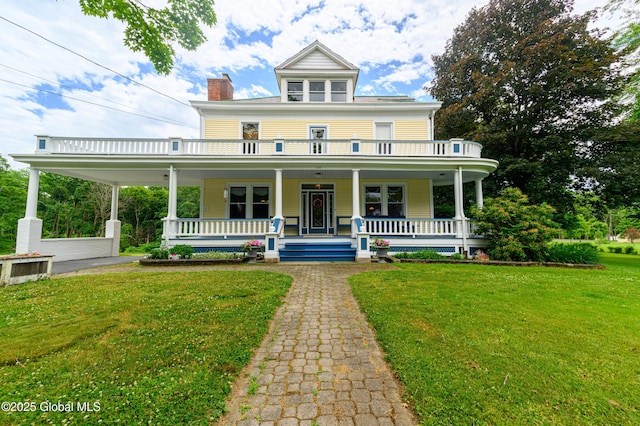 view of front of house with a porch, a front yard, and a chimney