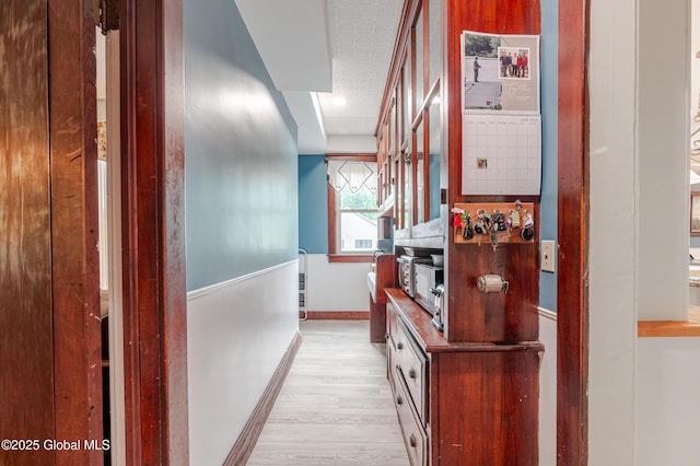 hall with light wood-style floors and baseboards