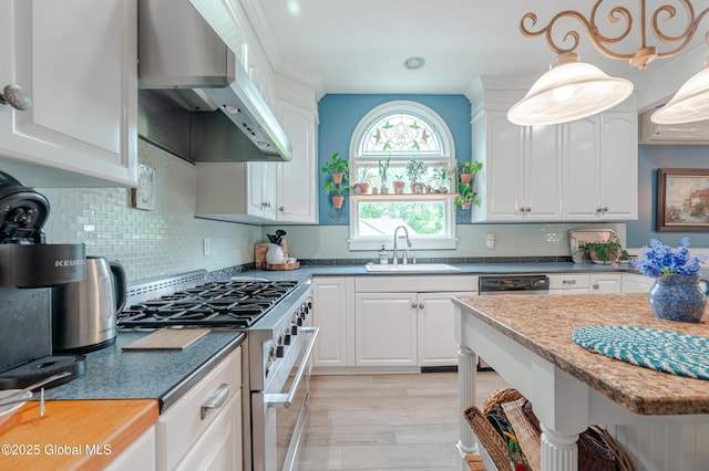 kitchen featuring wall chimney exhaust hood, stainless steel stove, white cabinetry, a sink, and tasteful backsplash