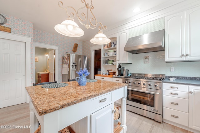 kitchen featuring appliances with stainless steel finishes, wall chimney exhaust hood, open shelves, wallpapered walls, and white cabinetry