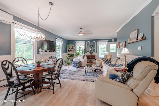 dining space with crown molding, a wall mounted air conditioner, light wood-type flooring, a ceiling fan, and wainscoting