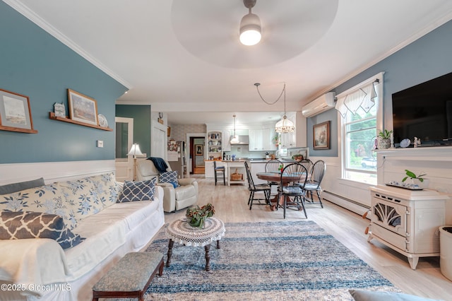 living room with baseboard heating, a wall unit AC, crown molding, light wood-type flooring, and a wainscoted wall