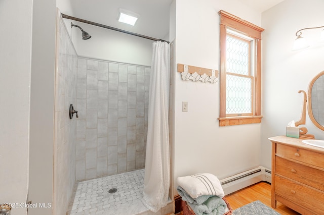 bathroom featuring a baseboard heating unit, a tile shower, and vanity