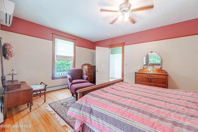 bedroom with multiple windows, a baseboard radiator, wood finished floors, and ceiling fan