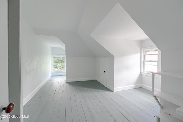 additional living space with vaulted ceiling, hardwood / wood-style floors, and baseboards