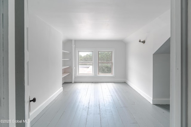 additional living space with hardwood / wood-style flooring, baseboards, and lofted ceiling