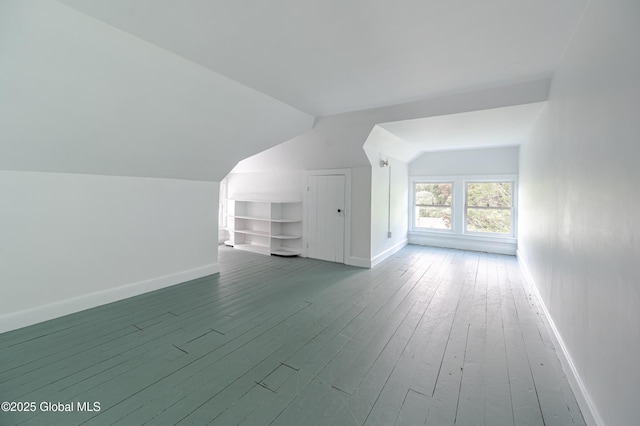 additional living space featuring vaulted ceiling, baseboards, hardwood / wood-style flooring, and built in features