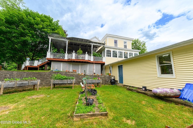 rear view of property with a garden, a wooden deck, and a yard