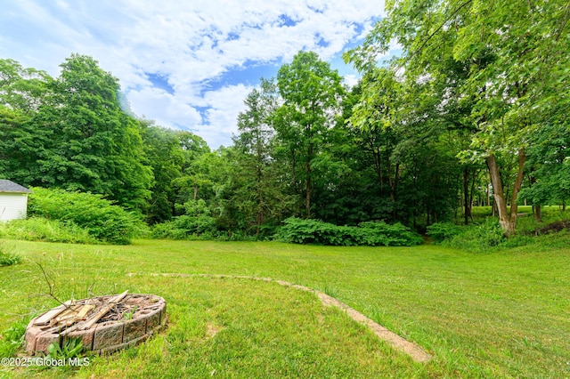 view of green lawn featuring an outdoor fire pit