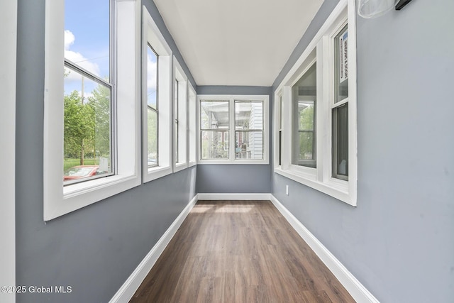 unfurnished sunroom featuring wood finished floors, plenty of natural light, and baseboards