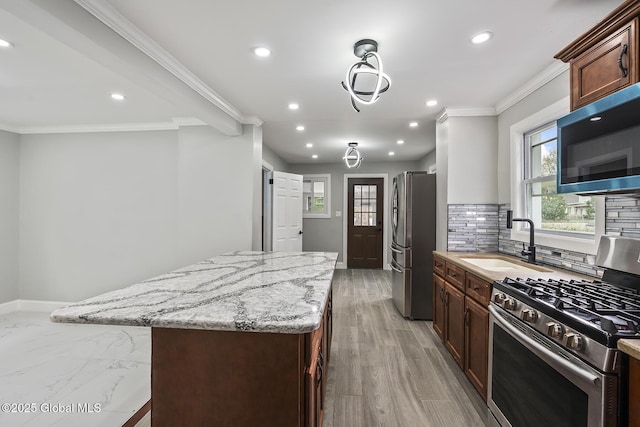 kitchen with appliances with stainless steel finishes, a sink, a center island, recessed lighting, and light stone countertops